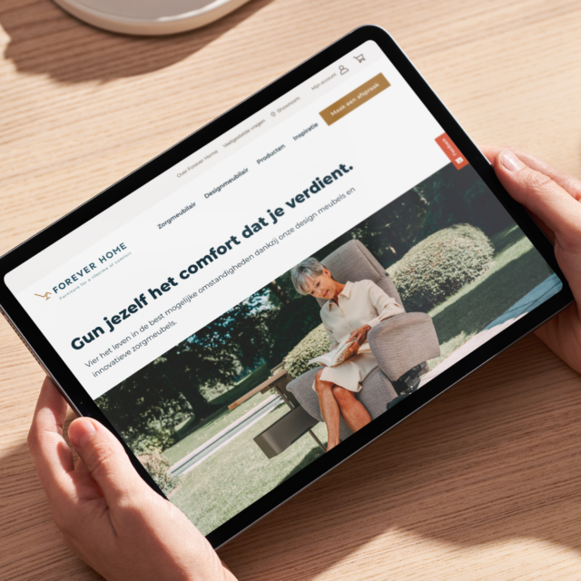 A tablet held in the hands, showing the Forever Home website