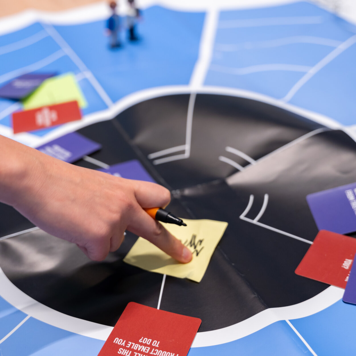 Persoon die wijst naar een post-it op een cirkeldiagram in een workshop