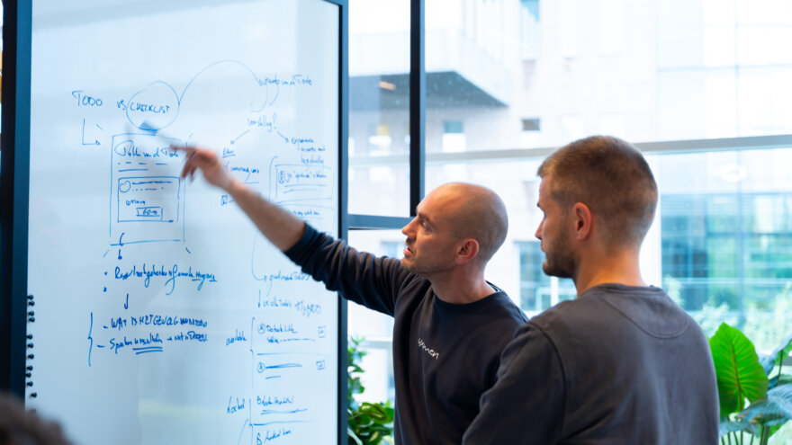 Bram en Bert die aan een whiteboard staan en een informatiearchitectuur uittekenen